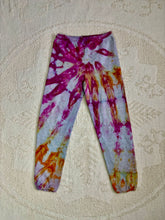 Load image into Gallery viewer, Vintage ice-dyed sweatpants featuring a mix of vibrant magenta, orange, and yellow hues against a light gray base. The pattern radiates outward, creating a bold and unique design. The pants have an elastic waistband and cuffs.