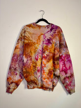 Load image into Gallery viewer, Hand-dyed vintage sweatshirt with a unique ice dye pattern in warm tones of orange, pink, and brown. Features a crewneck, long sleeves, and ribbed cuffs. Displayed on a black hanger against a white background.
