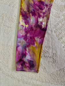 vintage ice-dyed sweatpants featuring a blend of deep magenta, golden yellow, and hints of white, creating a marbled effect. The ice dye technique produces organic, abstract patterns with soft color transitions. The pants have an elastic waistband and a slim fit.